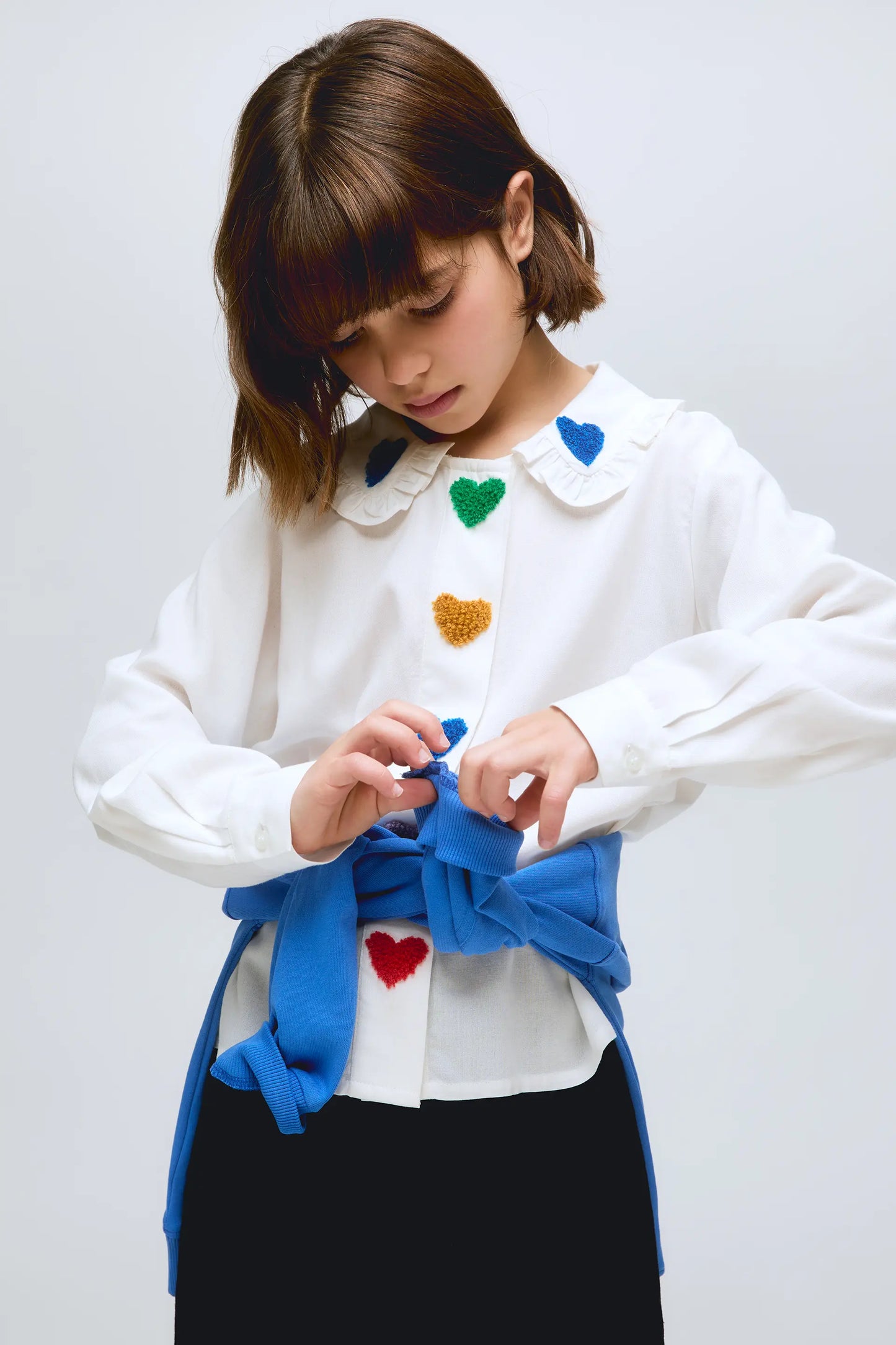 Camisa blanca con detalle de corazones multicolor y cuello con volantes.