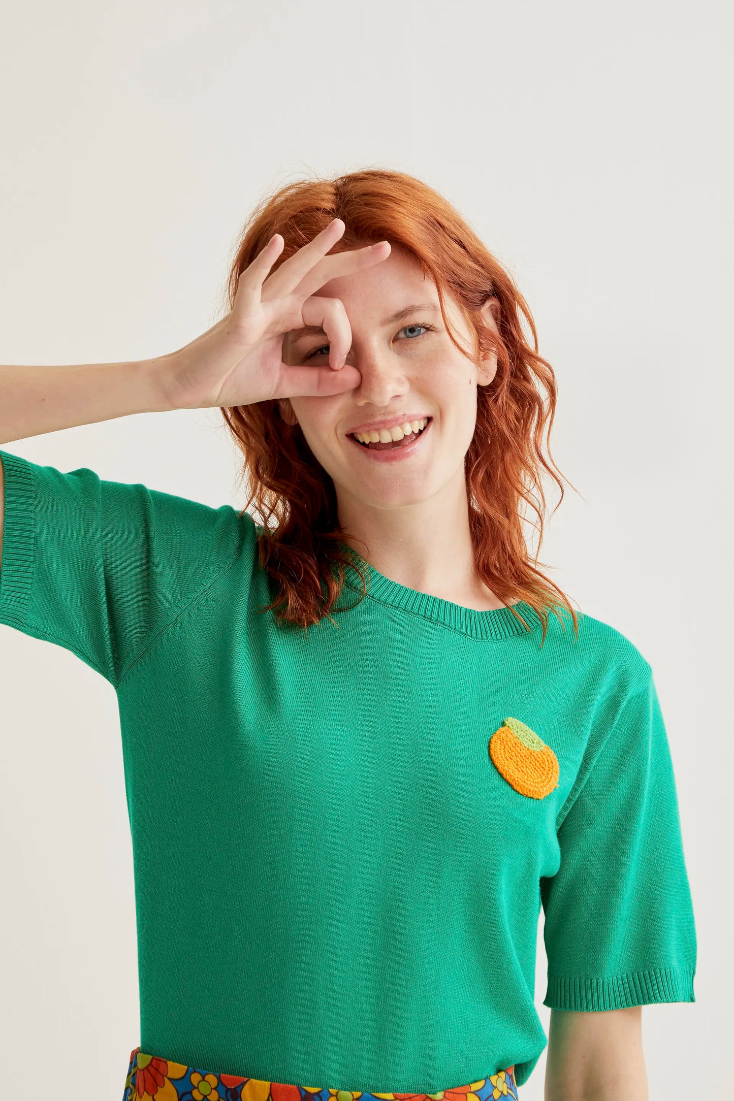 Top de punto verde con bordado de naranja