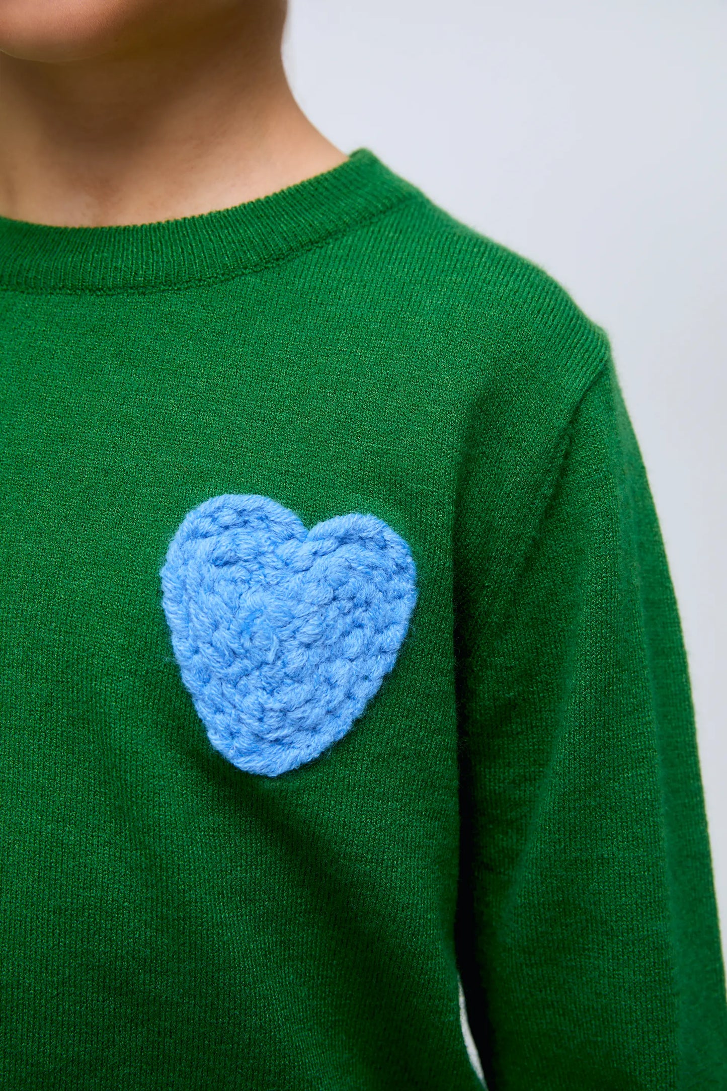Maglione verde lavorato a maglia per bambina con ricamo a forma di cuore blu