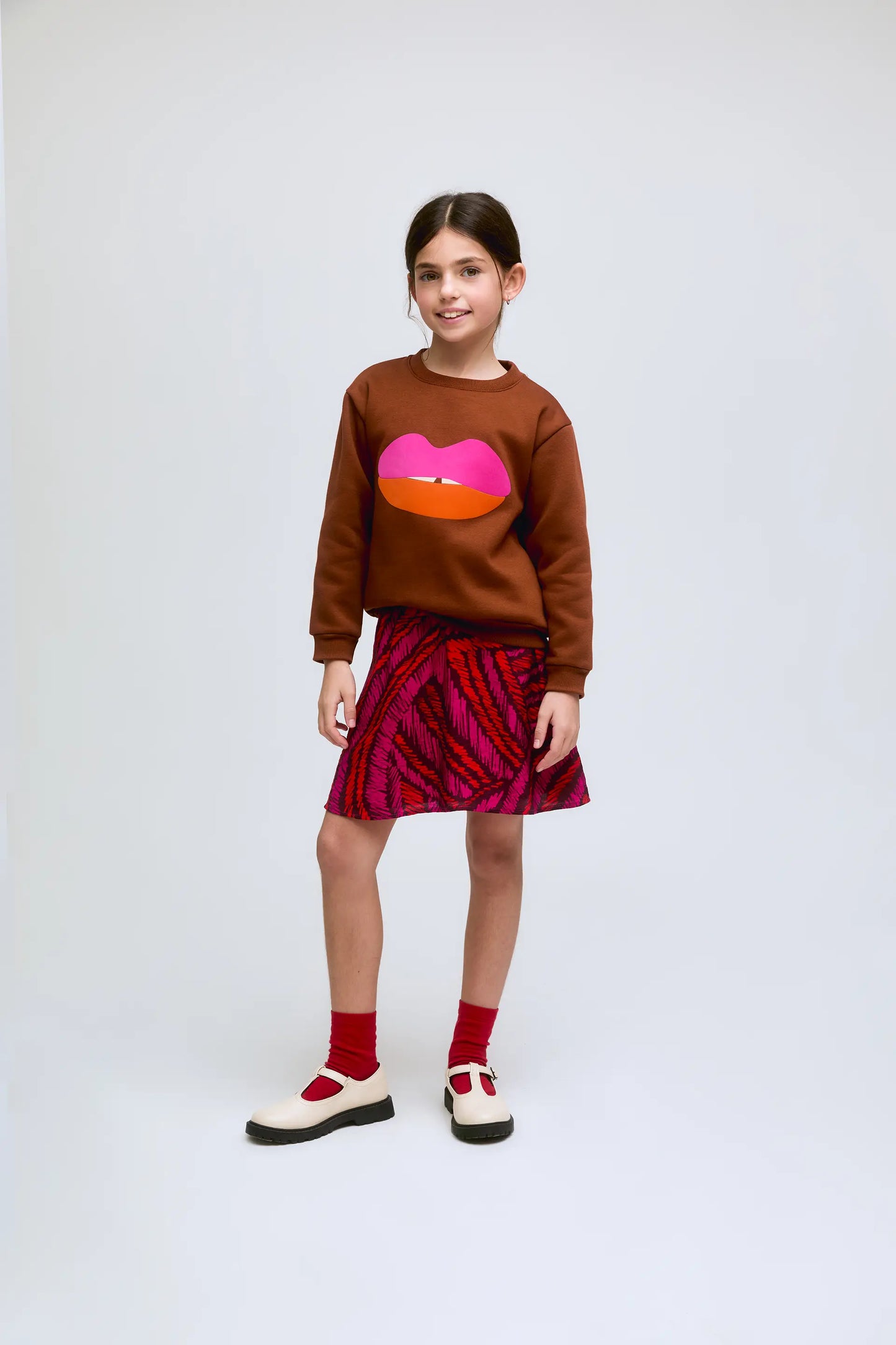 Sudadera de niña marrón con estampado de labios en fucsia y naranja.