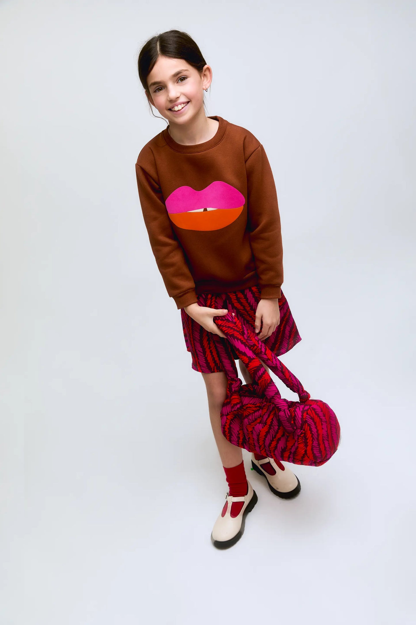 Sudadera de niña marrón con estampado de labios en fucsia y naranja.