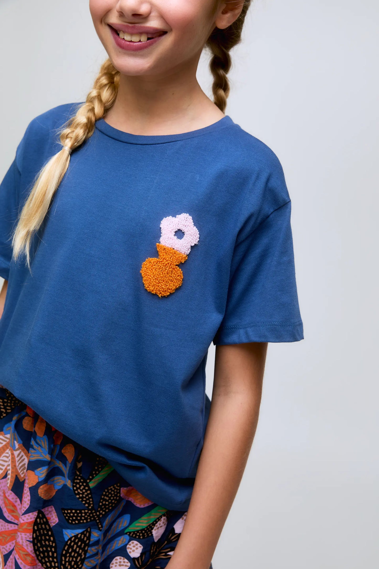 Maglietta blu da bambina con ricami floreali.