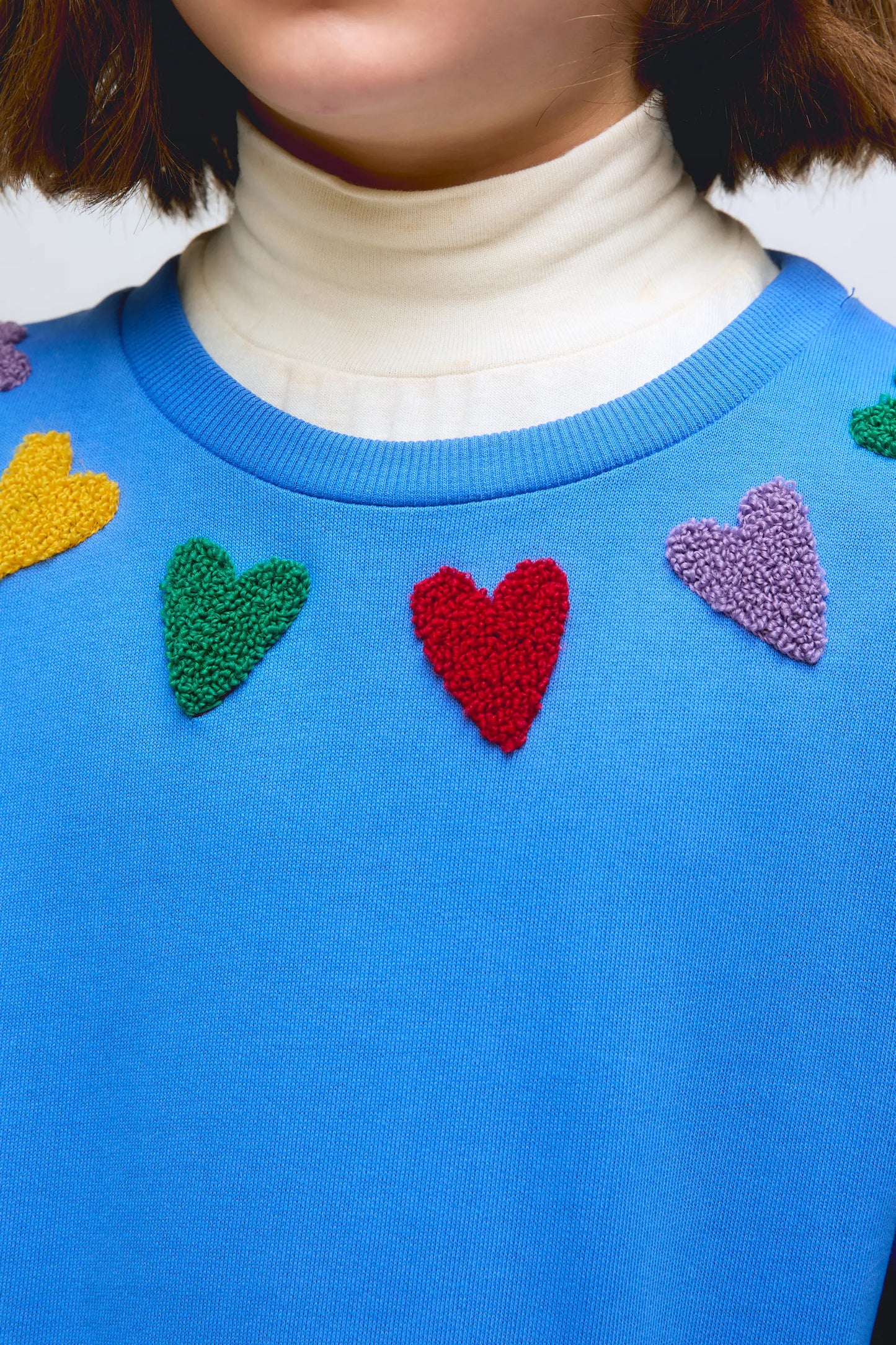 Blue sweatshirt with embroidered heart details.