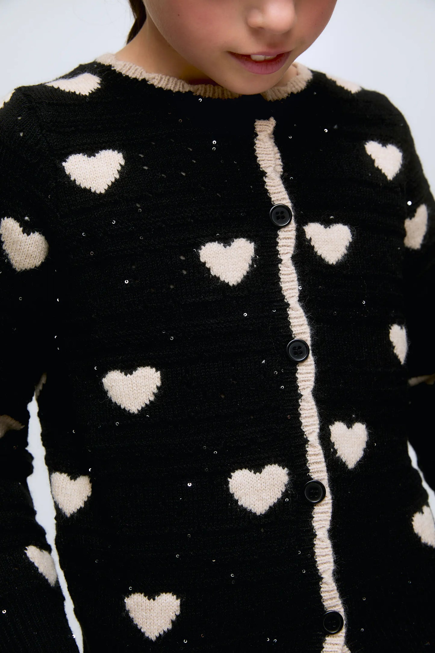 Black girl's cardigan with white hearts and front buttons.
