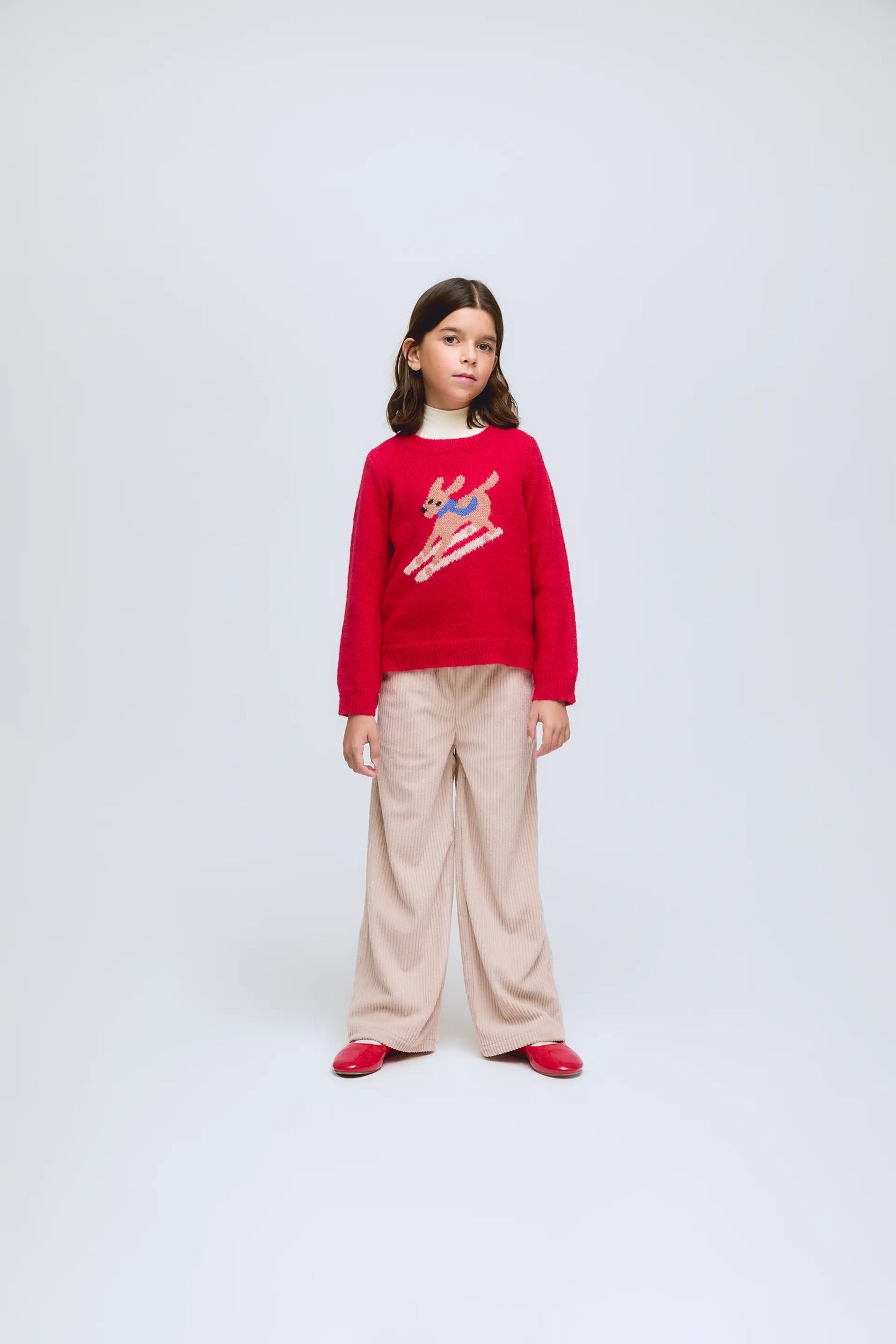 Red knitted sweater with a skiing dog design.