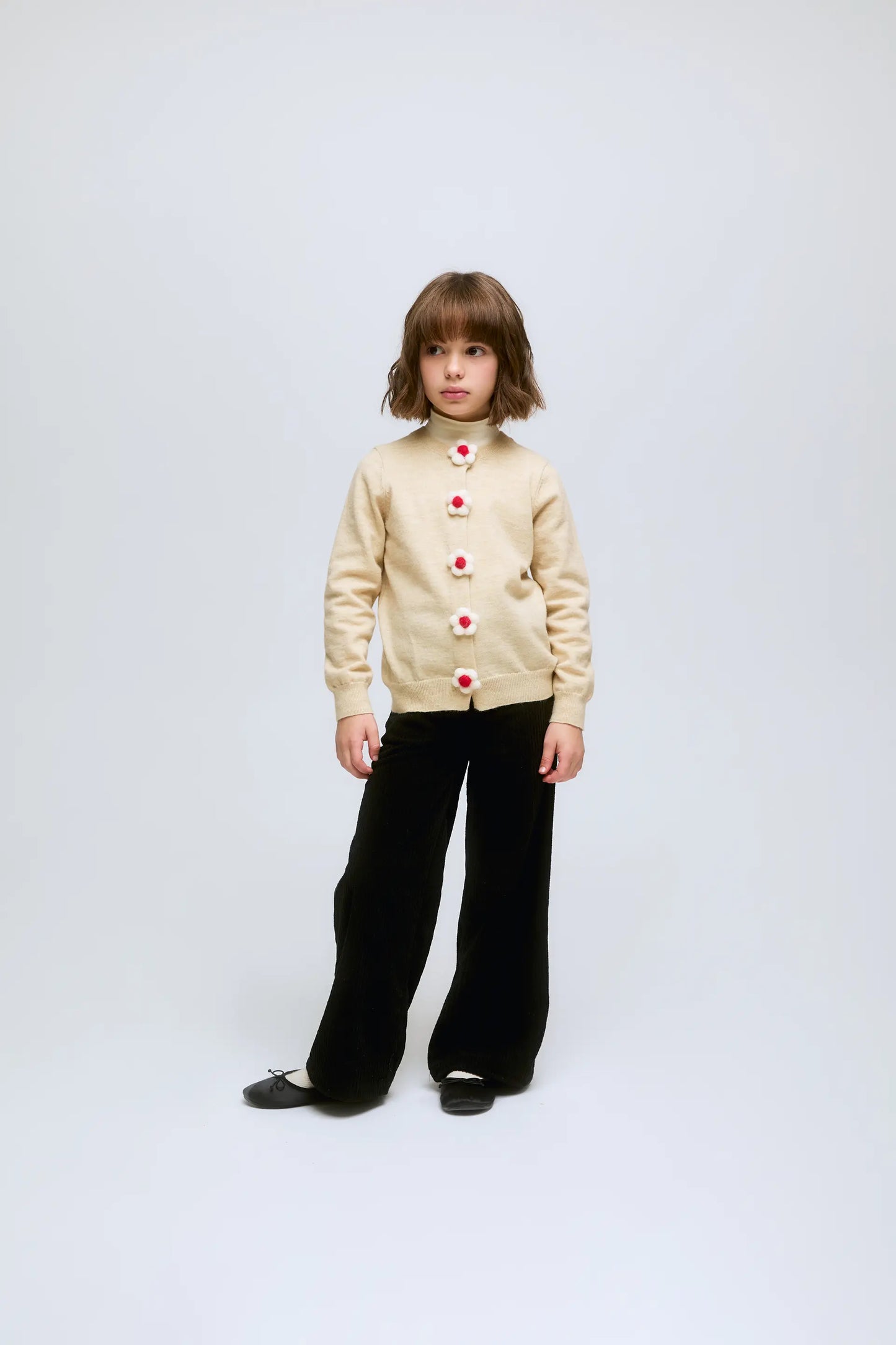 Cardigan beige de punto con botones en forma de flor.