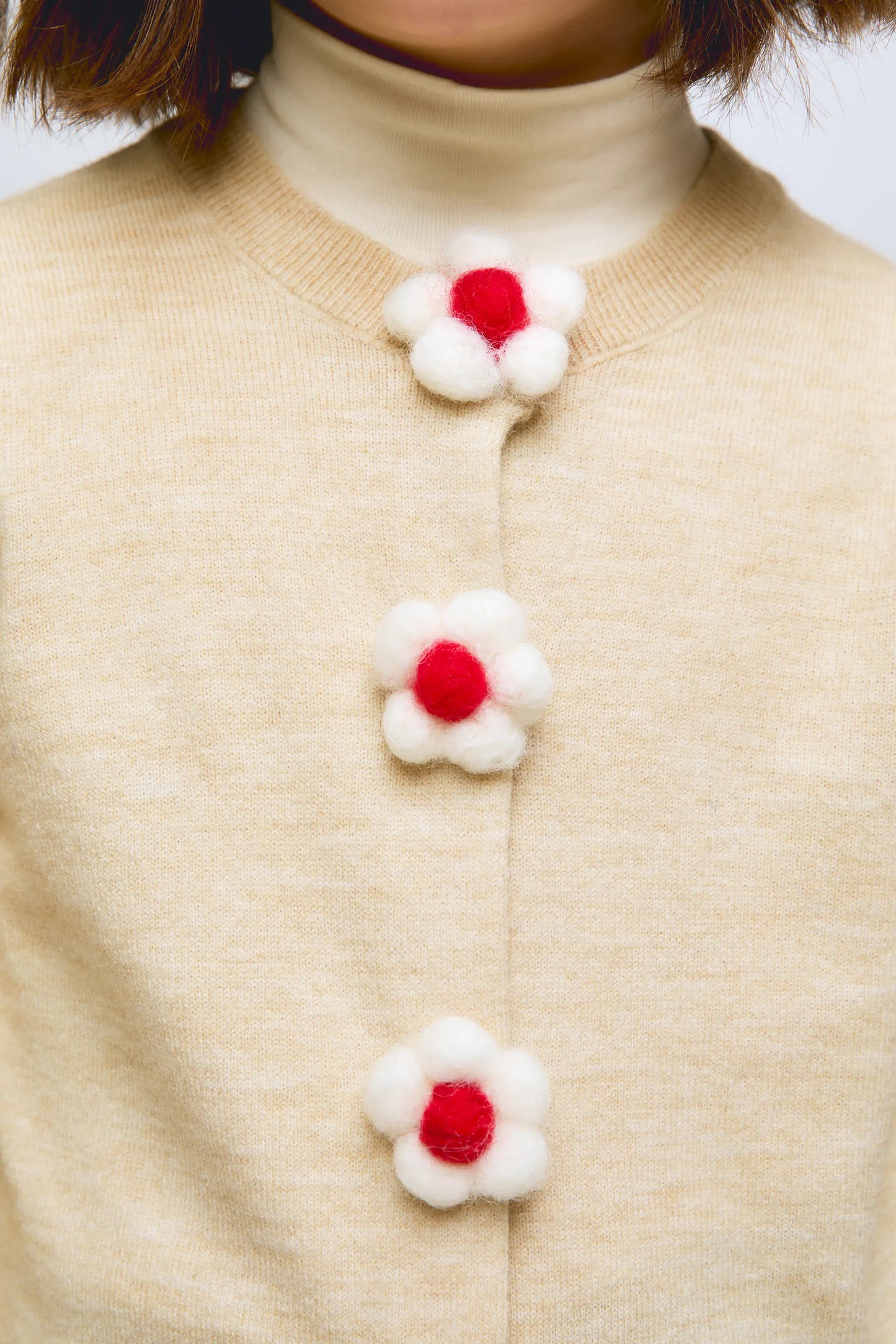 Cardigan beige de punto con botones en forma de flor.