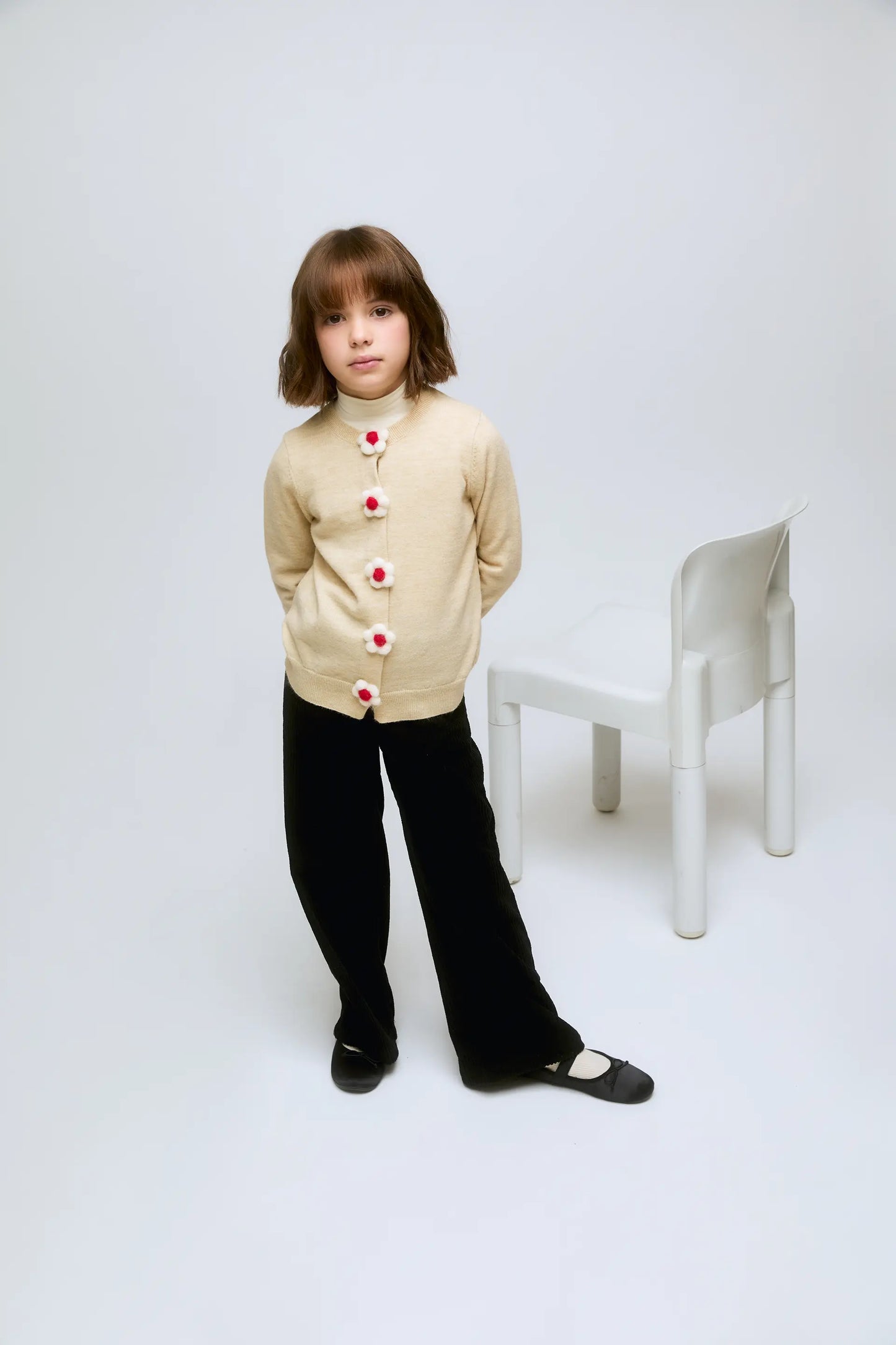 Cardigan beige de punto con botones en forma de flor.