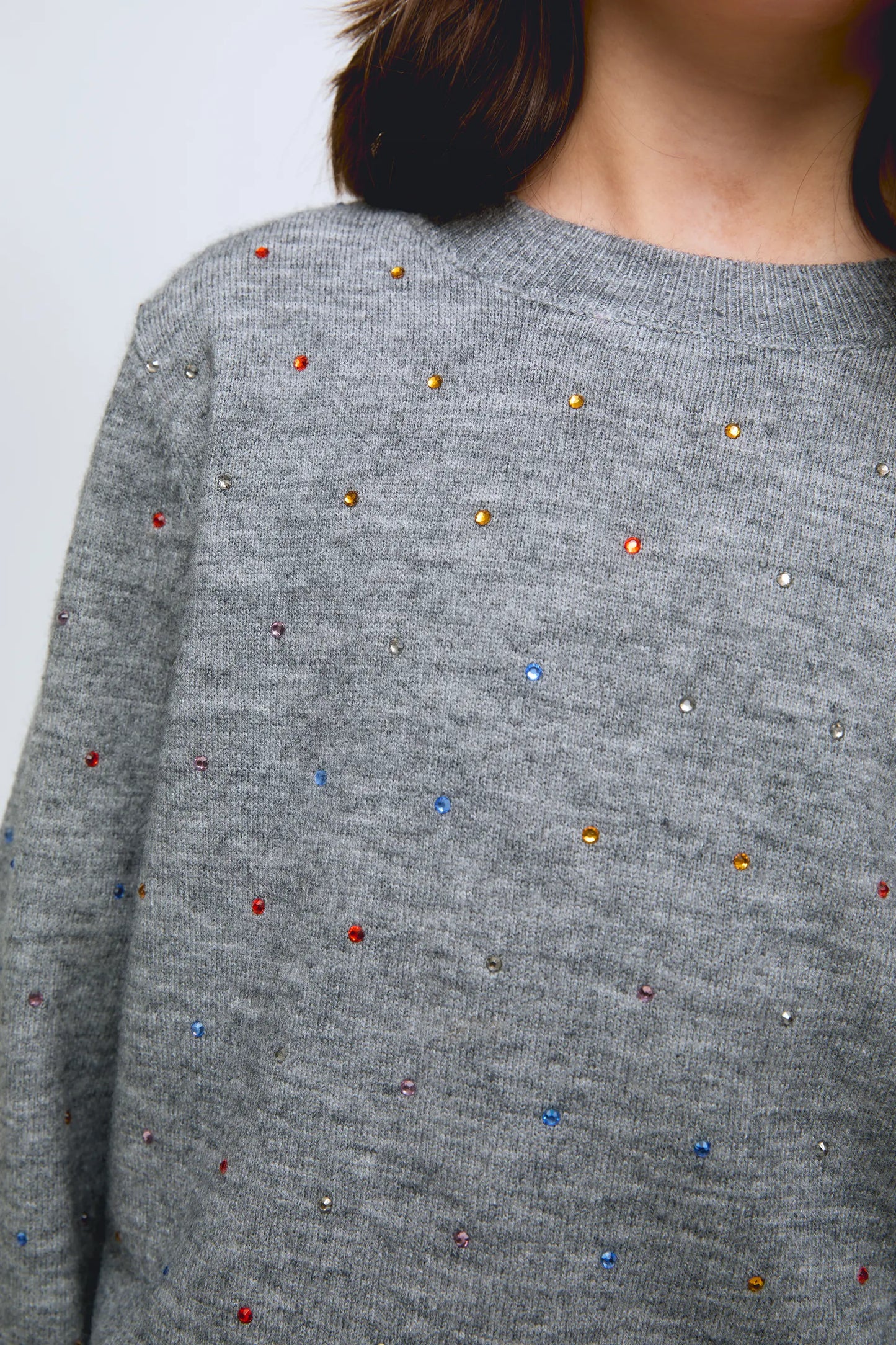 Grey knitted girl's sweater with small glitter appliqués.
