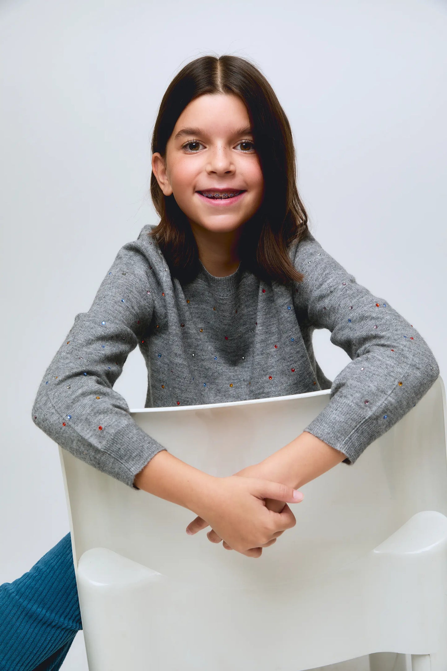 Grey knitted girl's sweater with small glitter appliqués.