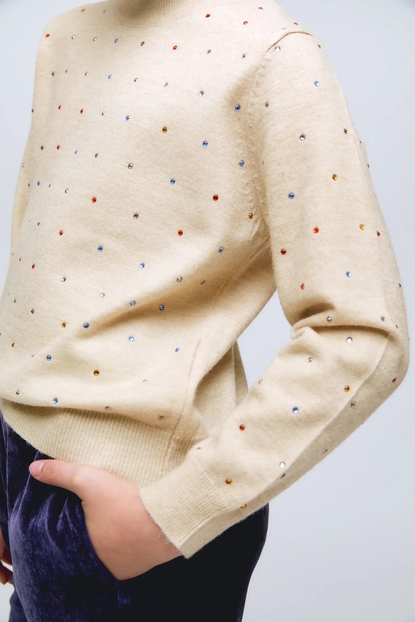 Beige knitted girl's sweater with small glitter appliqués.