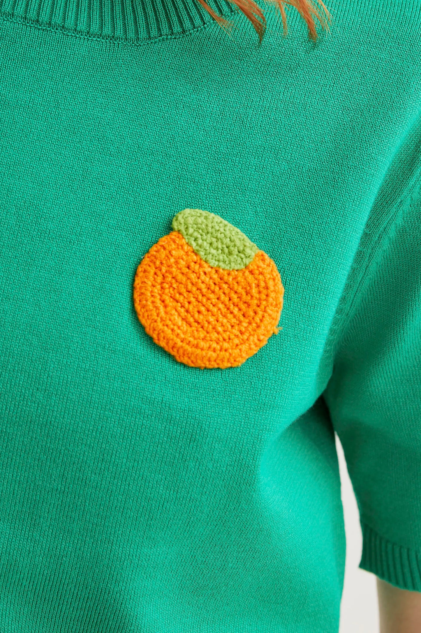Top de punto verde con bordado de naranja