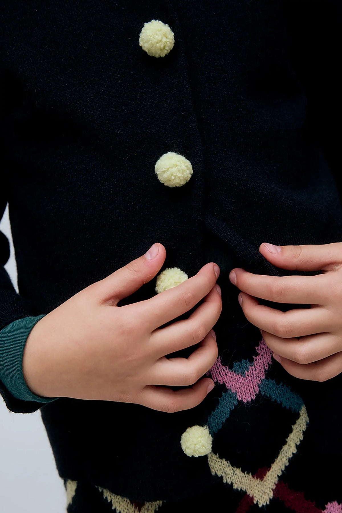 Cardigan nero da bambina con bottoni a pompon
